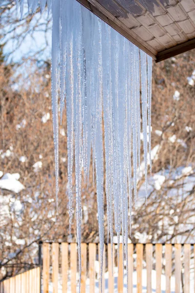 Icicles hang from the snowy roof of a mountain cottage — Stock fotografie