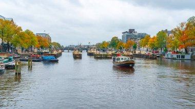 Amsterdam, Netherlands - October 15, 2019: Colorful houses and Boats on Amsterdam Canal. Autumn in Amsterdam