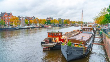 Amsterdam, Netherlands - October 15, 2019: Colorful houses and Boats on Amsterdam Canal. Autumn in Amsterdam