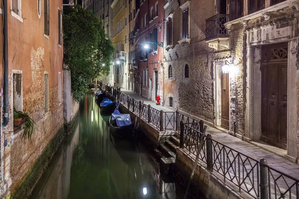 Narrow canal with boats and vintage houses at dusk. Venice city at night, Italy. Traditional Venice street in twilight.