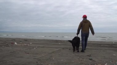 Alman çoban köpeği ve sahibi Karadeniz, Poti, Gürcistan kıyılarında yürürler.