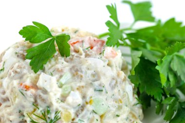 Çeşitli haşlanmış sebzelerin sirke salatası maydanozu beyaz tabakta siliyor.