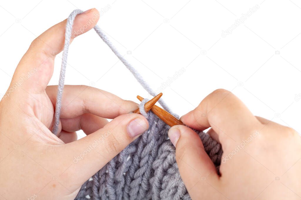 Women's hands knit from grey wool on white background, hobby
