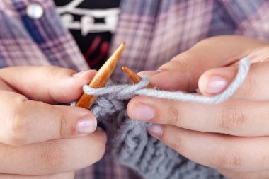 Kadın elleri gri yünden örülür. El örgüsü, hobi.