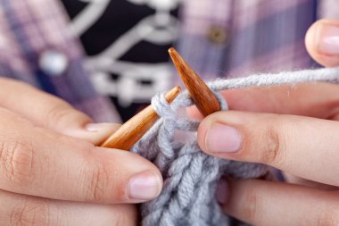 Kadın elleri gri yünden örülür. El örgüsü, hobi.