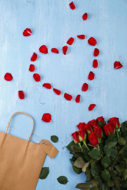 Kalp mavi ahşap tahta üzerinde kırmızı gül yaprakları.