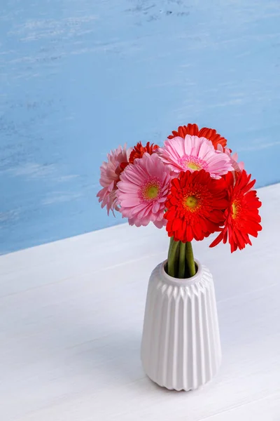 Gerbera flowers in vase on wooden background.
