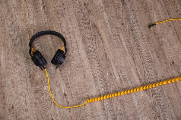 Headphones with yellow cable. Wooden background. — Stock Photo, Image