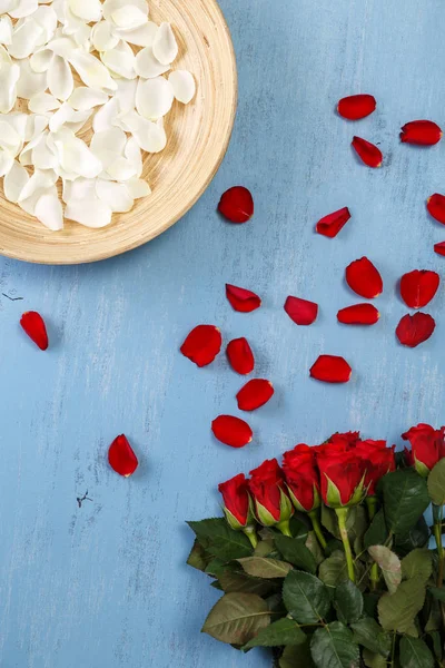 Mavi ahşap arka plan üzerinde kırmızı gül yaprakları.