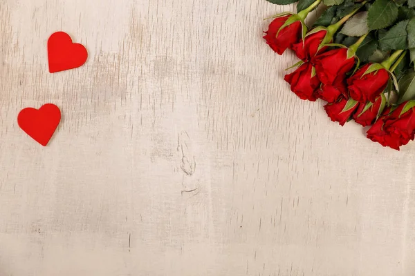 Röda rosor med hjärtan på trä bakgrund. — Stockfoto