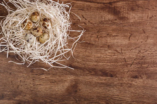Huevos de codorniz en nido de paja. Fondo de madera . — Foto de Stock