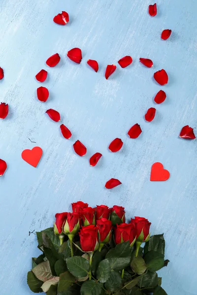 Serce czerwone płatki róż, niebieski płyty drewniane. — Zdjęcie stockowe