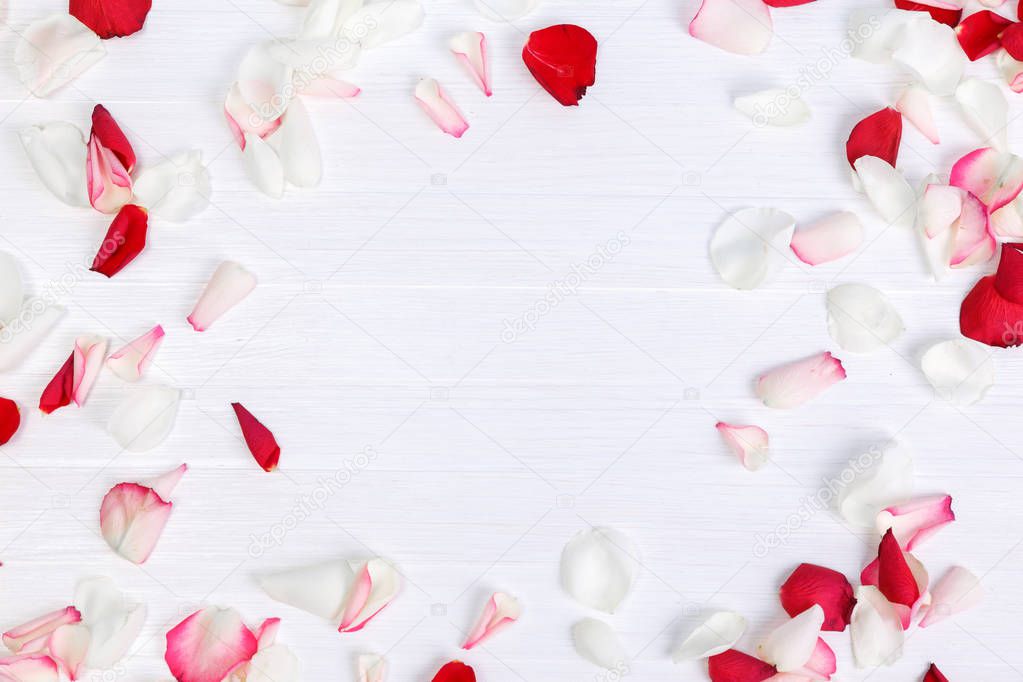 Petals of roses on white wooden background.