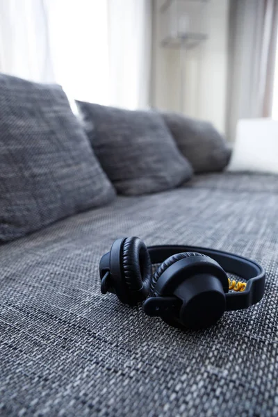 Kuulokkeet makaavat sohvalla. Musiikillinen käsite . — kuvapankkivalokuva