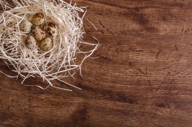 Bıldırcın yumurtası saman içinde iç içe. Ahşap arka plan.