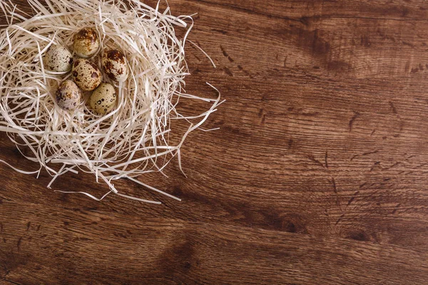 Bıldırcın yumurtası saman içinde iç içe. Ahşap arka plan.