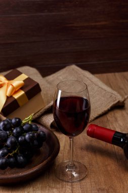 Kırmızı şarap. Bardağı üzüm şubesi ile. Hediye kutusu.