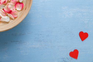 Kırmızı kalp ve gül yaprakları mavi ahşap tahta üzerinde.