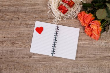 Kalp, hediye kutuları ve defter ile pembe güller.