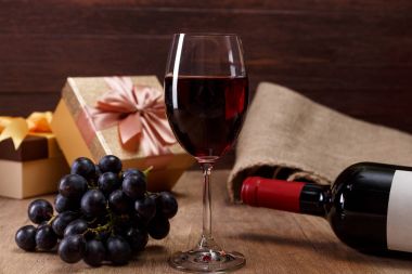 Kırmızı şarap. Bardağı üzüm şubesi ile. Hediye kutusu.