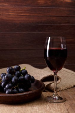 Kırmızı şarap. Bardağı üzüm şubesi ile.