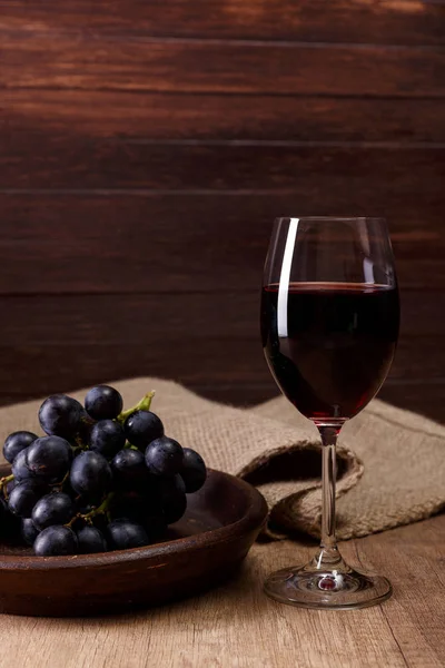 Kırmızı şarap. Bardağı üzüm şubesi ile.