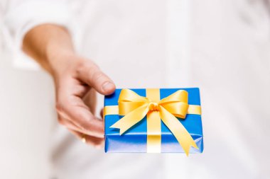 Erkek el ile şerit mavi hediye kutusu tutarak.