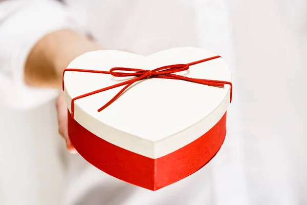 Férfi kezében egy ajándék szív alakú doboz. — Stock Fotó
