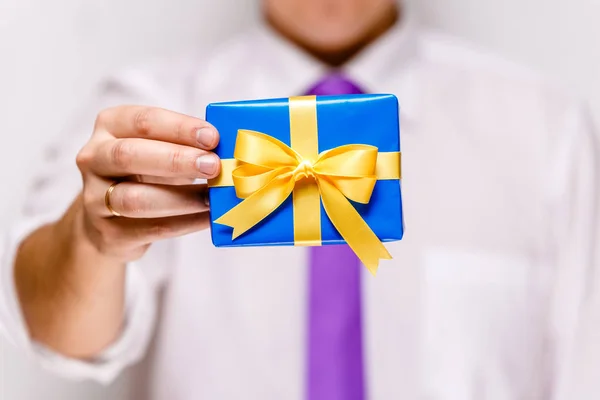 Male hand holding a blue gift box with ribbon. — Stock Photo, Image