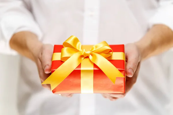 Male hands holding a red gift box with ribbon. — Stock Photo, Image