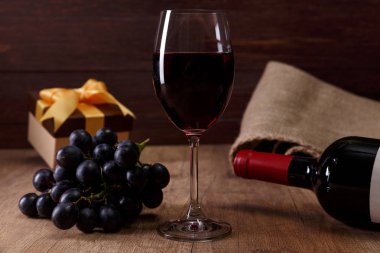 Kırmızı şarap. Bardağı üzüm şubesi ile. Hediye kutusu.