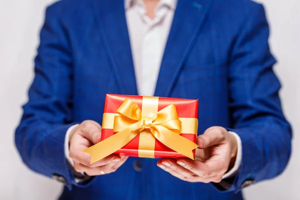 Male hands holding a red gift box with ribbon. — Stock Photo, Image