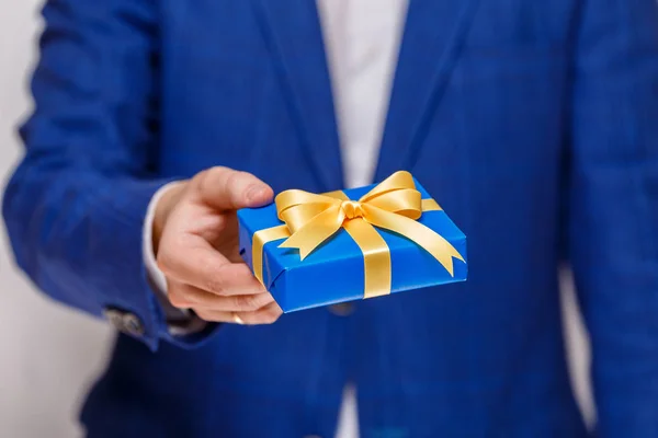 Male hand holding a blue gift box with ribbon. — Stock Photo, Image