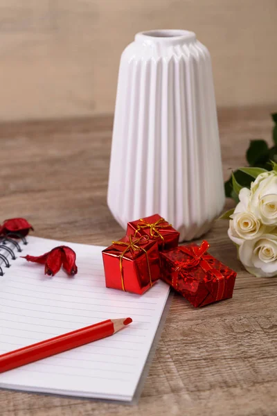 White roses with gift boxes and notepad. — Stock Photo, Image