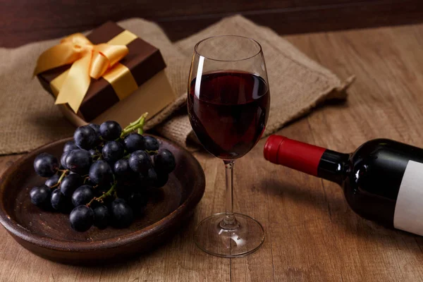 Kırmızı şarap. Bardağı üzüm şubesi ile. Hediye kutusu.