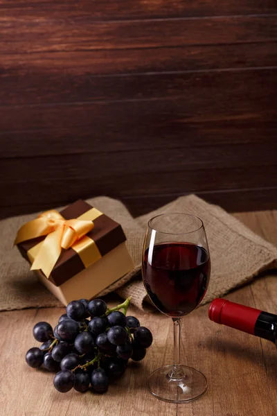 Red wine. Wineglass with grapes branch. Gift box.