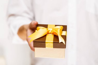 Erkek el bir hediye kutusu kurdele ile tutarak.