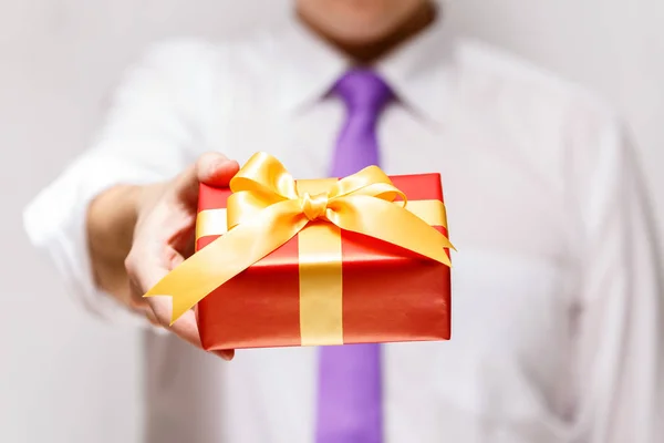 Male hand holding a red gift box with ribbon. — Stock Photo, Image
