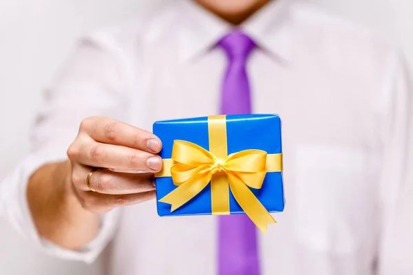 Male hand holding a blue gift box with ribbon. — Stock Photo, Image