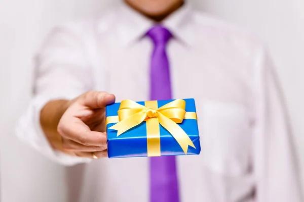 Male hand holding a blue gift box with ribbon. — Stock Photo, Image