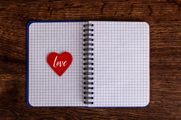 Red heart on the open notebook. Love design.