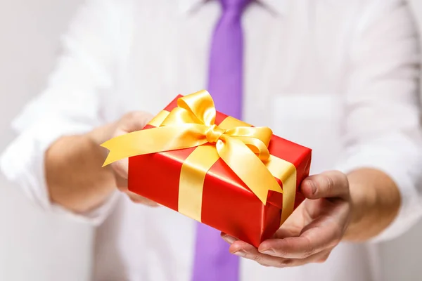 Male hands holding a red gift box with ribbon. — Stock Photo, Image