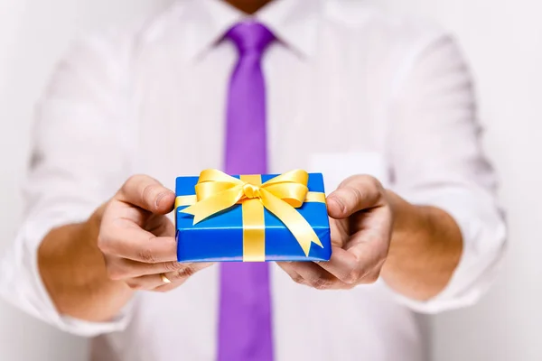 Male hands holding a blue gift box with ribbon. — Stock Photo, Image
