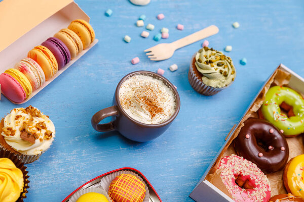 Cupcakes, macaroons and donuts. Mug with cream.