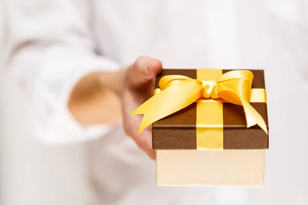 Male hand holding a gift box with ribbon.