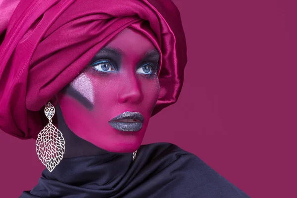 Bela jovem com cabelo envolto em turbante. Retrato criativo sobre fundo vermelho . — Fotografia de Stock