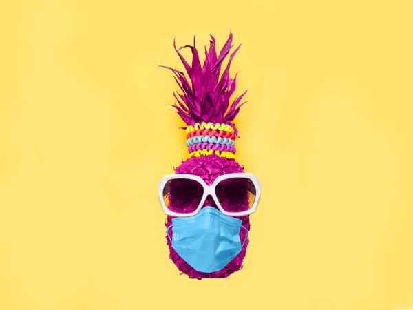 Güneş gözlüklü ananas ve sarı arka planda tıbbi maske.