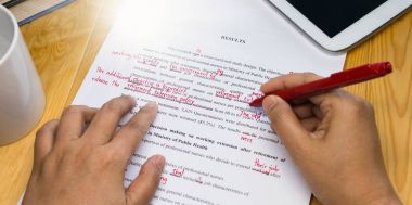 hand holding red pen over proofreading text clipart