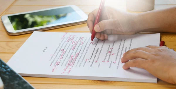 Mão segurando caneta vermelha sobre o texto de revisão — Fotografia de Stock