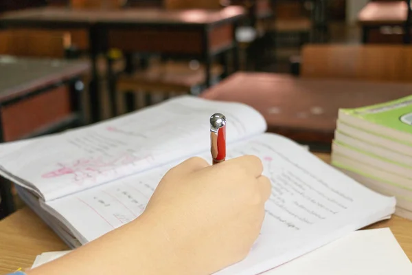 Die Hand des Lehrers mit dem roten Stift, der die Hausaufgaben des Schülers überprüft — Stockfoto